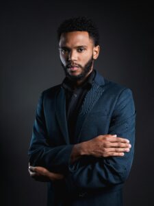 Portrait of a confident businessman in a dark suit on a black background.